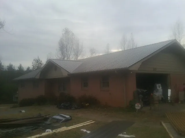 Gray metal roof on a stucco house with an attached garage in Camden